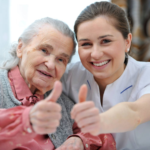 female caregiver and old senior woman doing thumbs up
