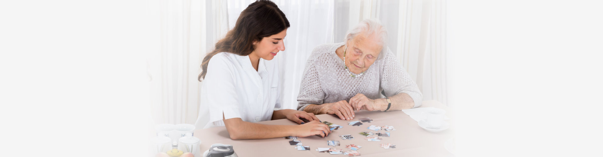 female caregiver and her old woman patient solving the puzzle