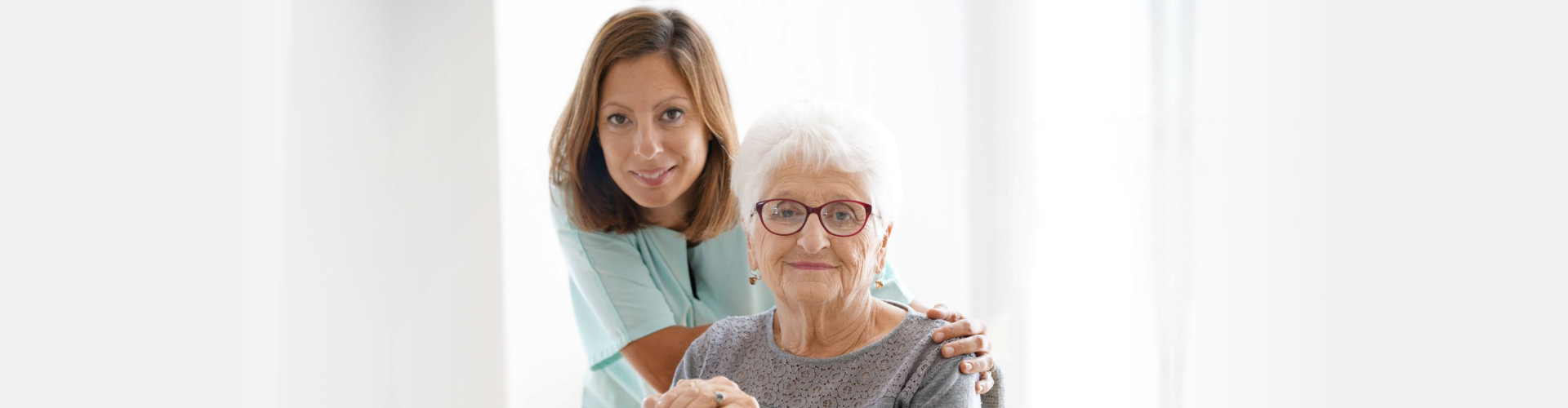 smiling female caregiver and her old woman patient wearing eye glasses